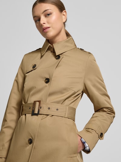 Modelka kobieca nosi Mantel mit Stoffgürtel od Jake*s Casual w kolorze beżowym, materiał z bawełną, krój slim fit, pasek, kołnierz, kieszenie, zapięcie na guziki, długość tyłu w rozmiarze 36: 99 cm, szerokość ramion w rozmiarze 36: 40 cm, szerokość klatki piersiowej w rozmiarze 36: 41 cm, długość rękawa w rozmiarze 36: 64 cm, półzbliżenie górnej części ciała z przodu