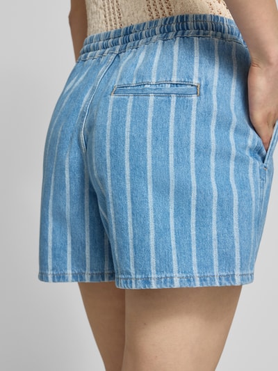 Vrouwenmodel draagt Relaxed Fit Jeansshorts uit puur katoen van Marc O'Polo Denim, blauwe denimlook, gestreept, elastische tailleband, steekzakken, achterzak, cropped lengte, detailopname achterkant.