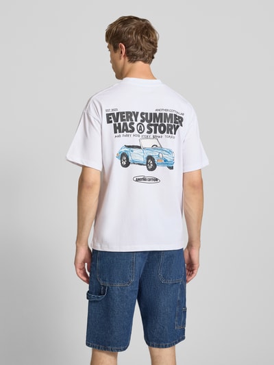 Mężczyznamodel nosi biały T-Shirt mit Label-Prints und Rundhalsausschnitt von ANOTHER COTTON LAB, czysta bawełna, krój relaxed fit, nadruk z logo, okrągły dekolt, długość tyłu w rozmiarze M: 68 cm, cała sylwetka z tyłu