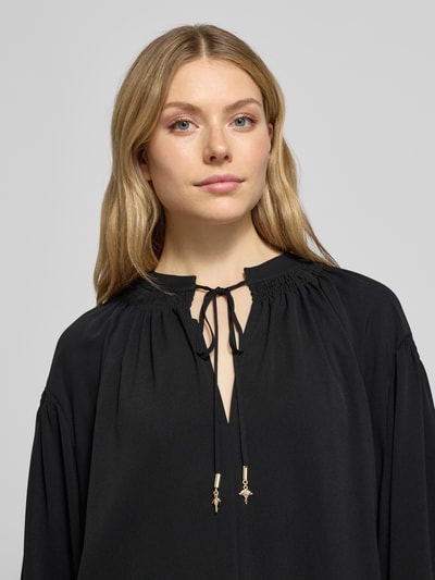 Kobiece model prezentuje Blusenshirt mit Raffungen Modell 'Brigida' von JOOP! w czarnym kolorze, wycięcie w kształcie łezki, luźny krój, długi rękaw, długość tyłu 64 cm, długość rękawów 56 cm, zbliżenie na górną część ciała.