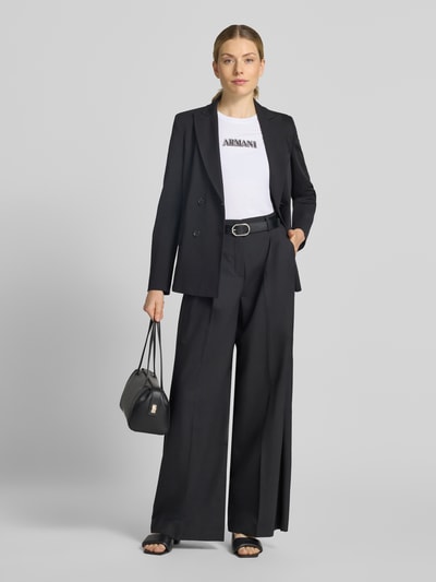 Frauenmodel trägt Slim Fit T-Shirt aus Baumwolle von Armani Exchange in Weiß mit Strasssteinbesatz, kombiniert zu schwarzem Anzug, Ganzkörperansicht von vorne. Rückenlänge bei Größe S: 59 cm, Rundhalsausschnitt, reine Baumwolle.