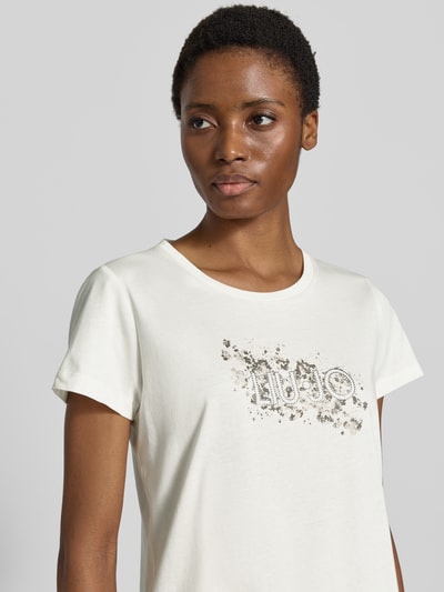 Vrouwenmodel draagt T-shirt met strass-steentjes van Lui Jo Sport van puur katoen met recht model, ronde hals, motiefprint; Nahaufnahme Oberkörper. Ruglengte bij maat S: 60 cm.