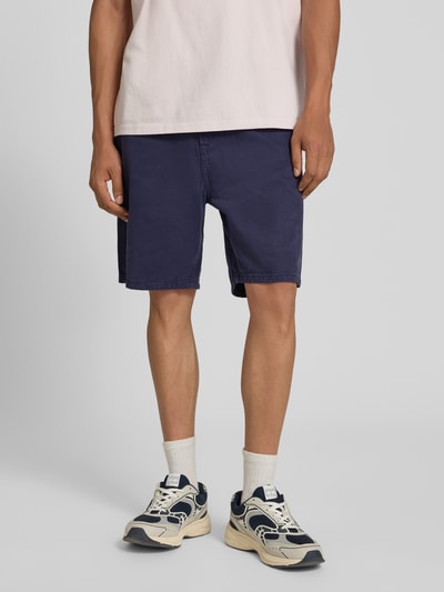 Männermodel trägt Bermudas von Jack & Jones aus reiner Baumwolle, Straight Fit, 5-Pocket-Design, Knopf-Reißverschluss, Ganzkörperansicht von vorne. Modell 'TONY ORIGINAL', Bundweite 42 cm, Innenbeinlänge 20 cm, dunkles Blau, glatte Textur.