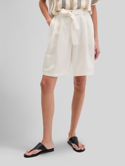 Frauenmodel trägt Relaxed Fit Shorts mit Leinen-Anteil von Marc O'Polo, Optik: Unifarben, Passform: Relaxed-Fit, High-Waist, Bundfalten, Stoffgürtel, Knopf und verdeckter Reißverschluss, helle Farbgebung, glatt fließende Textur, Nahaufnahme Oberschenkel.