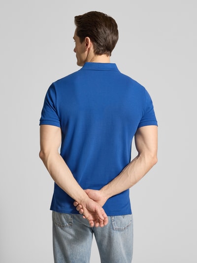 Männermodel trägt Regular Fit Poloshirt aus reiner Baumwolle von Polo Ralph Lauren, unifarben in Blau, Piqué-Struktur, Ganzkörperansicht Rückansicht.