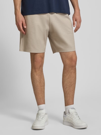 Mężczyzna nosi Straight Fit Shorts mit Viskose-Anteil von REVIEW, elastyczna mieszanka materiałów, kolor beżowy, Szerokość w rozmiarze M: 43 cm, Długość wewnętrzna nogawki: 19 cm, Ganzkörperansicht von vorne.
