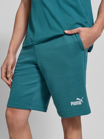Männermodel trägt Shorts mit Label-Stitching von PUMA PERFORMANCE in Türkis, Baumwoll-Mix, elastischer Bund, Nahaufnahme Oberschenkel.