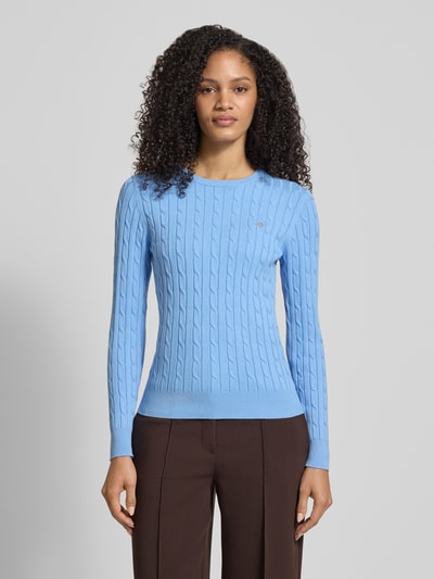 Vrouwenmodel draagt gebreide pullover met kabelpatroon en labelstitching van Gant, katoenmix met stretch, slim fit, ronde hals, ruglengte maat S 58 cm, mouwlengte maat S 61 cm, lichtblauw, gladde textuur, voorkant totaalbeeld.