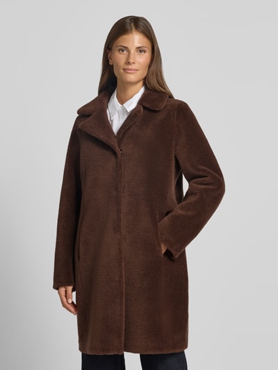 Frauenmodel trägt Wendemantel in Woll-Lammfell-Optik Modell 'VENUS' von OAKWOOD in Braun mit Reverskragen und Eingrifftaschen, Ganzkörperansicht von vorne.