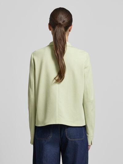 Modelka kobieca nosi Regular Fit Jacke mit Stehkragen od WHITE LABEL w jasnozielonym kolorze, elastyczna bawełna, naszywane kieszenie, pełna lista guzików; długość tyłu w rozmiarze 36: 57 cm, szerokość w rozmiarze 36: 50 cm, długość rękawa w rozmiarze 36: 65 cm; widok całej sylwetki od tyłu.