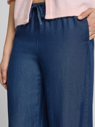 Frauenmodel trägt Wide Leg Hose aus Lyocell Modell 'CHARIS' von Only in Denim-Optik mit elastischem Bundabschluss und seitlichen Eingrifftaschen, Nahaufnahme Oberkörper.