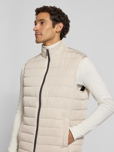 Männermodel trägt Steppweste mit Stehkragen und Eingrifftaschen von Christian Berg Men in Beige, dezente Streifen-Struktur, Nahaufnahme Oberkörper. Regular Fit, Reißverschluss, Rückenlänge 70 cm, Schulterbreite 44 cm, Brustweite 58 cm.