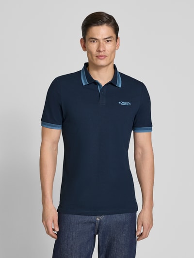 Männermodel trägt Regular Fit Poloshirt aus Baumwoll-Mix von s.Oliver RED LABEL, unifarben, kurzarm, Piqué-Textur, Ganzkörperansicht von vorne.