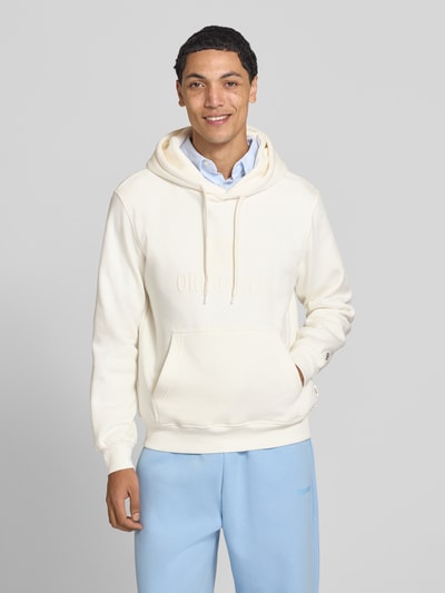 Männermodel trägt Hoodie aus Baumwoll-Mix Modell 'FREDERIKS' von JACK & JONES in Creme mit Kängurutasche, Ganzkörperansicht von vorne.