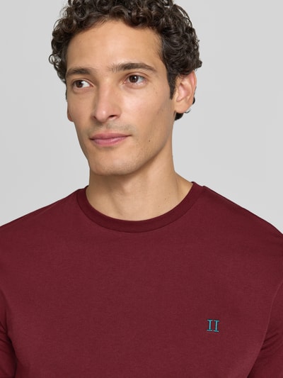 Männermodel trägt T-Shirt mit Logo-Stitching und Rundhalsausschnitt von Les Deux, Baumwoll-Mix, Straight Fit, Nahaufnahme Oberkörper.