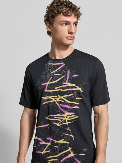 Männermodel trägt Herren T-Shirt von Salomon, Modell 'Kout', Gerader-Schnitt, Rundhalsausschnitt, Logo- und Motiv-Print, Nahaufnahme Oberkörper.