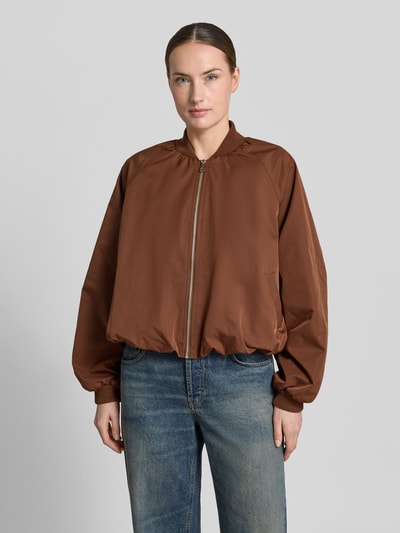 Frauenmodel trägt Blouson mit elastischen Ärmelabschlüssen und Reißverschluss von Zero in Braun, Loose-Fit, Stehkragen, Ganzkörperansicht von vorne, Rückenlänge 52 cm, Schulterbreite 40 cm, Brustweite 50 cm, Ärmellänge 55 cm, Struktur glattes Material.