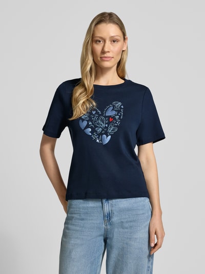 Frauenmodel trägt Relaxed Fit T-Shirt aus reiner Baumwolle von Tom Tailor in Optik: Unifarben mit Motiv-Print, Rundhals, Kurzarm, Ganzkörperansicht von vorne.