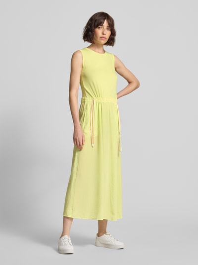 Frauenmodel trägt Maxikleid mit Kordelzug an der Taille von Marc Cain in Gelb, Baumwoll-Mix mit Stretch-Anteil, Taillierter Schnitt, Rundhalsausschnitt, Ganzkörperansicht von vorne.