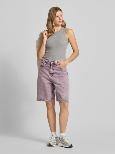 Frauenmodel trägt Straight Fit Jeansshorts im 5-Pocket-Design von Carhartt Work In Progress in Lila aus Reine Baumwolle, Ganzkörperansicht von vorne.