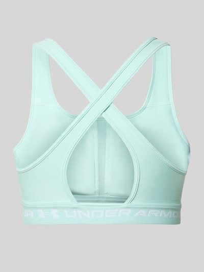 Kobiece modelka ma na sobie Slim Fit SportBH mit Logo-Print od Under Armour, elastyczna mieszanka materiałów, krój slim fit, nadruk z logo, wycięcie na plecach. Widok całej sylwetki od tyłu.