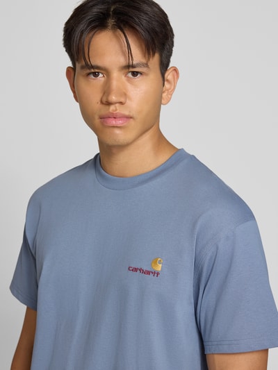 Męski model nosi Regular Fit T-Shirt aus reiner Baumwolle Model 'American Script' von Carhartt Work In Progress, niebieski, detal z logo, kontekst: Męski t-shirt z bawełny, krój regular fit, długość tyłu w rozmiarze M: 75 cm, Ganzkörperansicht von vorne.