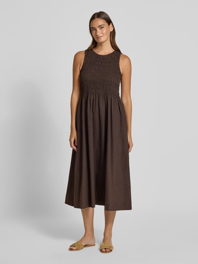 Frauenmodel trägt Midikleid aus Baumwoll-Leinen-Mix mit Eingrifftaschen von Smith and Soul in Braun, taillierte Passform, Rundhalsausschnitt, rückseitiger Schlüsselloch-Ausschnitt, Rückenlänge bei Größe S 120 cm, Brustweite 36 cm, Ganzkörperansicht von vorne.