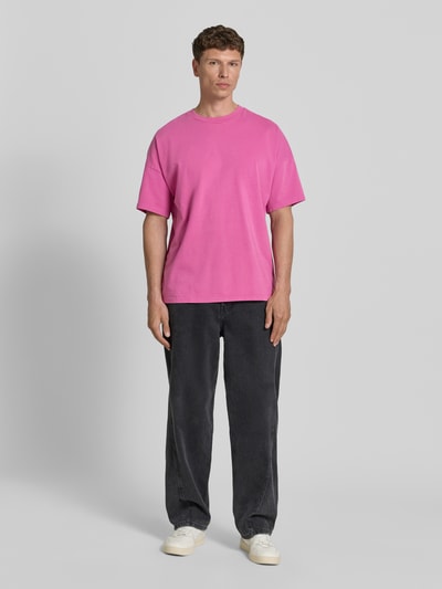 Männermodel trägt T-Shirt mit geripptem Rundhalsausschnitt Modell 'FIZVALLEY' von American Vintage in Pink, Loose Fit, Ganzkörperansicht von vorne.