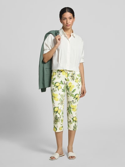 Modelka nosi Slim Fit Jeans mit floralem Allover-Print von Marc Cain z elastycznej mieszanki bawełny, 5 kieszeni, zapięcie na guzik i zamek błyskawiczny, szerokość w rozmiarze 36: 38 cm, długość wewnętrzna nogawki w rozmiarze 36: 53 cm, jasne kolory, wzór z cytrynami, gładka tekstura, pełny widok od przodu
