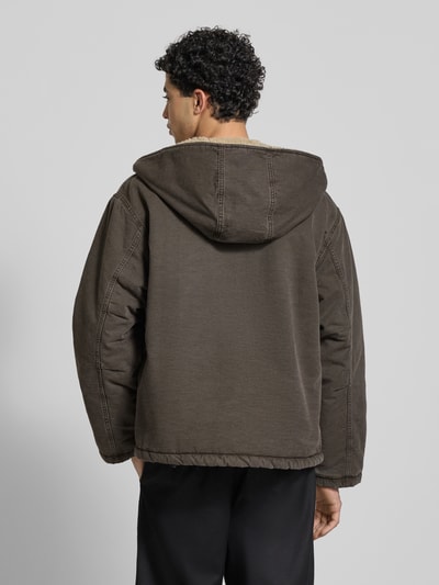 Männermodel trägt Jacke mit Zweiwege-Reißverschluss Modell 'MITCH' von Carhartt Work In Progress aus reiner Baumwolle in Braun, Regular Fit, Kapuze, sichtbare Nähte, Rückenansicht, Ganzkörperansicht Rückansicht.