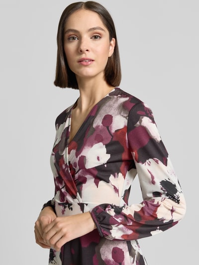 Frauenmodel trägt Midikleid in Wickel-Optik mit V-Ausschnitt von ZABAIONE, floraler Allover-Look, Material-Mix, Nahaufnahme Oberkörper.
