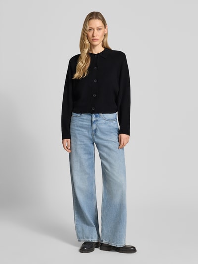 Frauenmodel trägt Cardigan aus Viskose-Mix mit Umlegekragen Modell 'Turea' von Someday in Schwarz, kombiniert mit Jeans, gerader Schnitt, Knopfleiste, Ganzkörperansicht von vorne.
