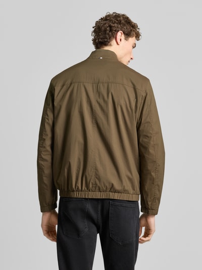 Männermodel trägt Jacke mit Stehkragen Modell 'Calvin' von Brax in Oliv, Baumwoll-Mix mit Stretch, gerade Form, Ganzkörperansicht Rückansicht.