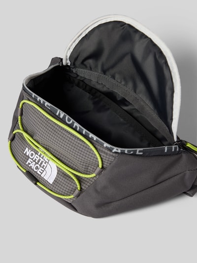 Produktfoto, schwarze Bauchtasche mit Label-Stitching Modell 'JESTER LUMBAR' von The North Face, Reißverschluss, gelbe Akzente, strukturierte Textur, verstellbarer Riemen, Maße 26x17x10 cm, Kontext Herren Bauchtasche