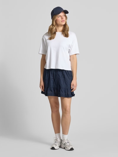 Frauenmodel trägt Regular Fit Mini-Skort aus reiner Baumwolle Modell 'KATTI' von Only in Dunkelblau mit strukturierter Stickerei, Ganzkörperansicht von vorne.