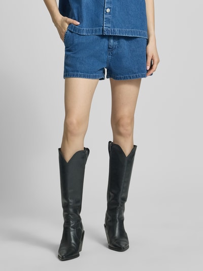 Frauenmodel trägt Shorts in Denim-Optik Modell 'Lova' von Carhartt Work In Progress aus Reine Baumwolle, Ganzkörperansicht von vorne. Eingriff- und Gesäßtaschen, Knopf- und Reißverschluss, ausgestellte Passform, Bundweite 38 cm, Innenbeinlänge 6 cm.
