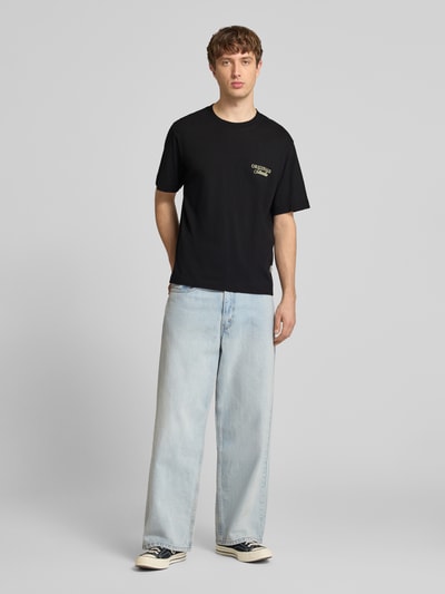 Männermodel trägt Herren T-Shirt mit Statement-Print Modell 'NORREBRO' von Jack & Jones, Schwarz, Reine Baumwolle, Gerader-Schnitt, Rundhalsausschnitt, Rückenlänge bei Größe M: 68 cm, Ganzkörperansicht von vorne.