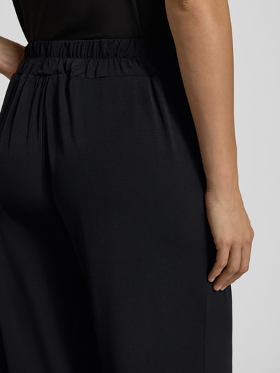 Vrouwenmodel draagt zwarte Stoffhose in verkürzter Passform Modell 'LIMA' van ICHI met elastische tailleband, detailopname heup. Materiaalmix met stretch, losse pasvorm, verkort model.