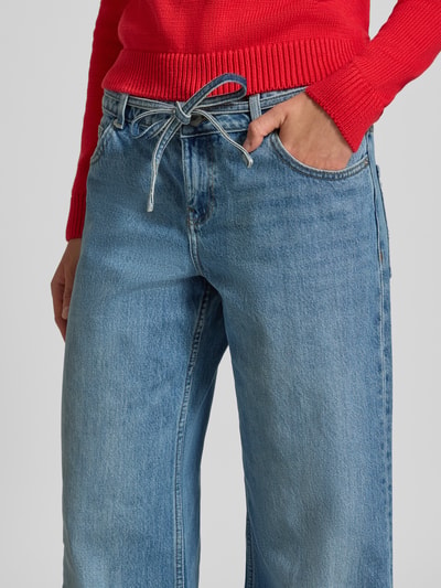 Frauenmodel trägt Wide Fit Jeans aus reiner Baumwolle von Review in Hellblau mit 5-Pocket-Design, Nahaufnahme Oberkörper.