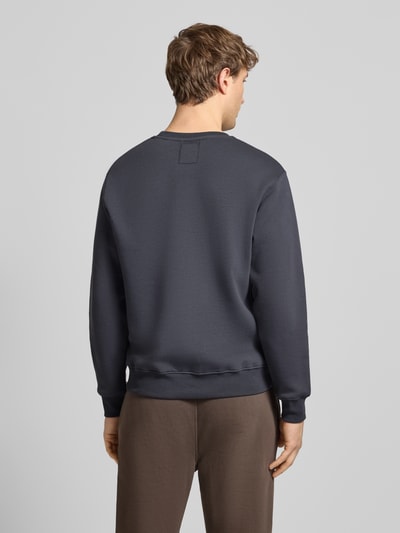 Männermodel trägt Sweatshirt mit gerippten Abschlüssen von Alpha Industries in Dunkelgrau, Baumwoll-Mix, lockerer Schnitt, Rückenansicht, Ganzkörperansicht Rückansicht.