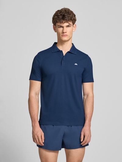 Männermodel trägt dunkelblaues Slim Fit Poloshirt mit Logo von Ellesse, Material-Mix mit Stretch-Anteil, Knopfleiste, Modell 'EDMOND', Rückenlänge bei Größe M 63 cm, Ganzkörperansicht von vorne.