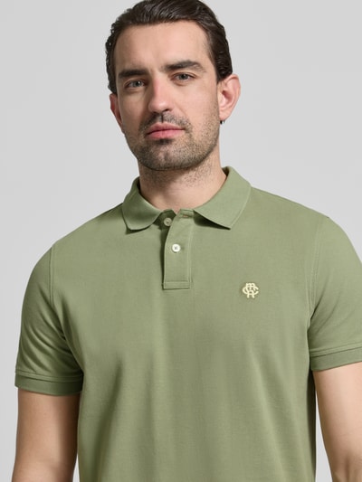 Männermodel trägt Slim Fit Poloshirt mit Logo-Stitching von MCNEAL in Hellgrün, reine Baumwolle, Nahaufnahme Oberkörper.