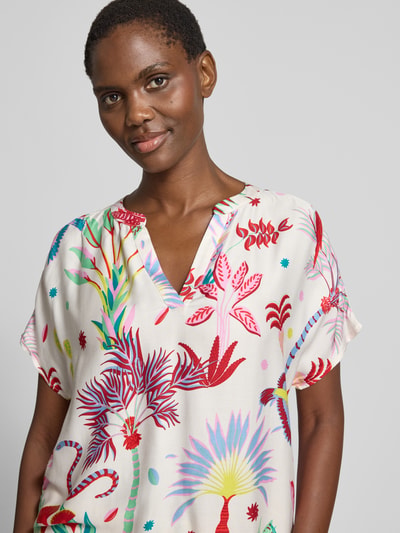 Modelka kobieca nosi Blusenshirt aus Viskose im Allover-Look od Milano Italy, czysta wiskoza, krój relaxed fit, wzór allover, dekolt w serek, długość tyłu w rozmiarze 36: 28 cm, długość rękawa w rozmiarze 36: 65 cm, wielokolorowy wzór roślinny na jasnym tle, widok na górną część ciała z przodu.