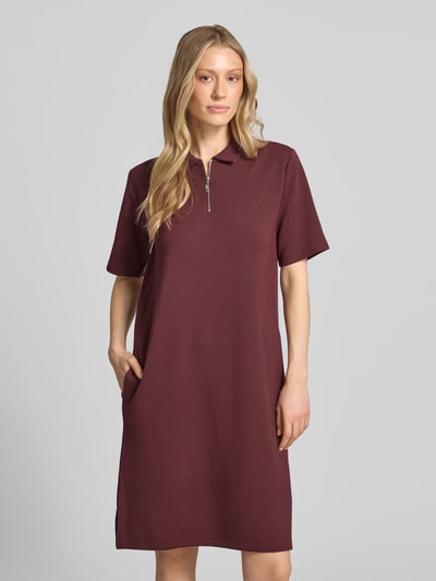 Frauenmodel trägt Polokleid mit kurzem Reißverschluss von Christian Berg Woman in Bordeaux, Material-Mix, Gerader-Schnitt, Midikleid, Polokragen, Nahaufnahme Oberkörper.
