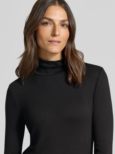 Frauenmodel trägt Longsleeve mit Rollkragen von someday, schwarze Farbe, feine Ripp-Struktur, Viskose-Mix, eng anliegend, Nahaufnahme Oberkörper.