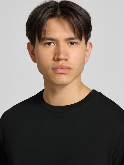 Männermodel trägt Oversized T-Shirt Modell 'FISHER' von Blend in Schwarz, reine Baumwolle, Rundhalsausschnitt, Nahaufnahme Oberkörper.