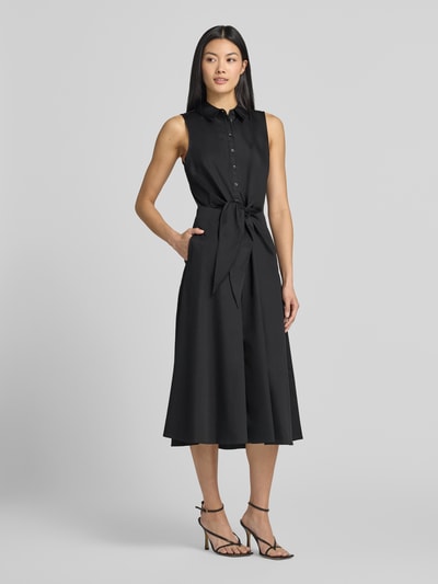 Frauenmodel trägt Midikleid mit Umlegekragen von Comma, schwarzer Baumwoll-Mix, taillierte Passform, Zierknoten, Knopfleiste, Ärmelloses-Design, Rückenlänge 118 cm bei Größe 36, Brustweite 45 cm, Ganzkörperansicht von vorne.
