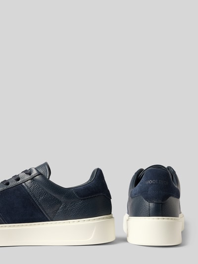 Produktfoto, Sneaker aus echtem Leder Modell 'Classic Court' von Woolrich in Dunkelblau, strukturierte Sohle, Kontrastbesatz, Seiten- und Rückansicht, Schafthöhe und Absatzhöhe bei Größe 44 sichtbar.