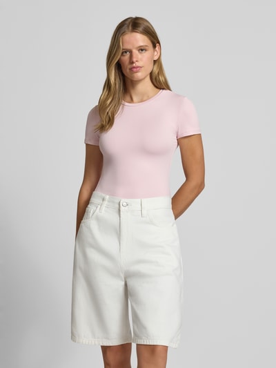 Vrouwenmodel draagt lichtroze slim fit t-shirt met ronde hals model 'LULA' van PIECES Dames, wit short, Ganzichsopname van voren.