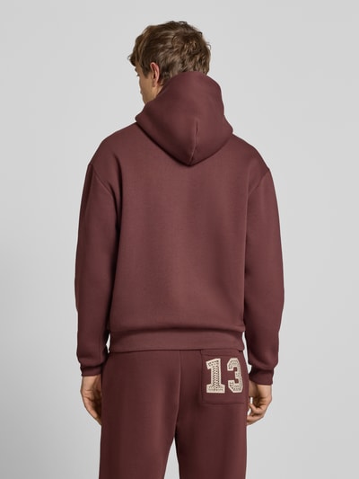 Männermodel trägt Hoodie mit Ketten-Stickerei und Känguru-Tasche von REVIEW in Braun, Baumwoll-Mix, Regular-Fit, Ganzkörperansicht Rückansicht.